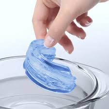 Hand holding a translucent blue object above a clear glass bowl.